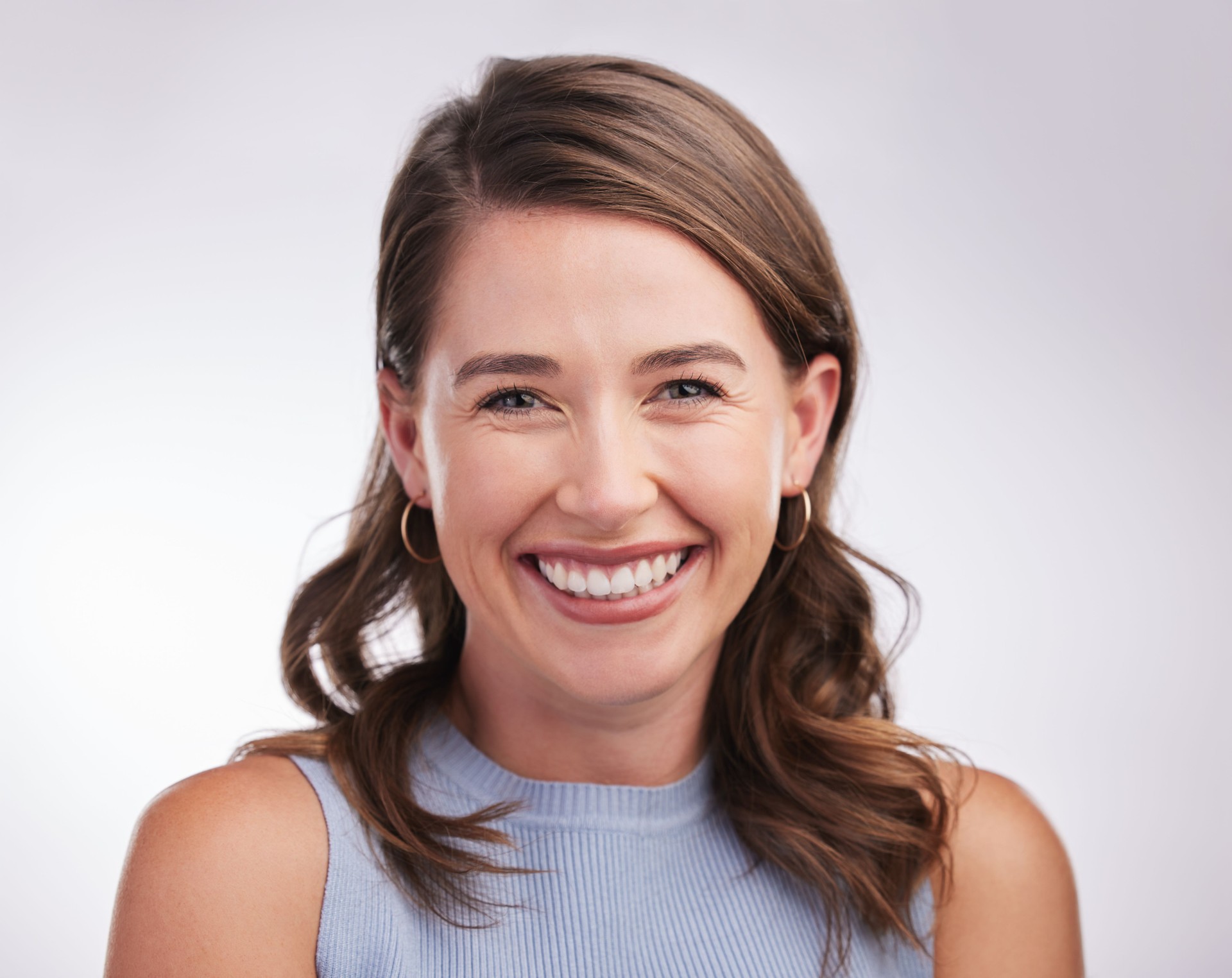 Studio portrait of a happy young woman posing against a grey background